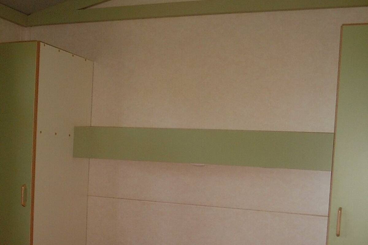 Una habitación con cama, paredes verdes y techo blanco.
