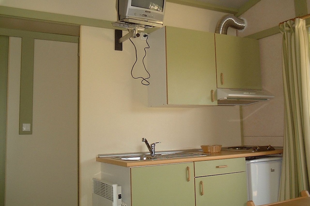 Cocina compacta con microondas integrado, un lavamanos y una pequeña encimera.