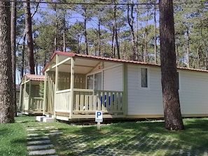 A row of small, single-story cabins with a porch, surrounded by trees.