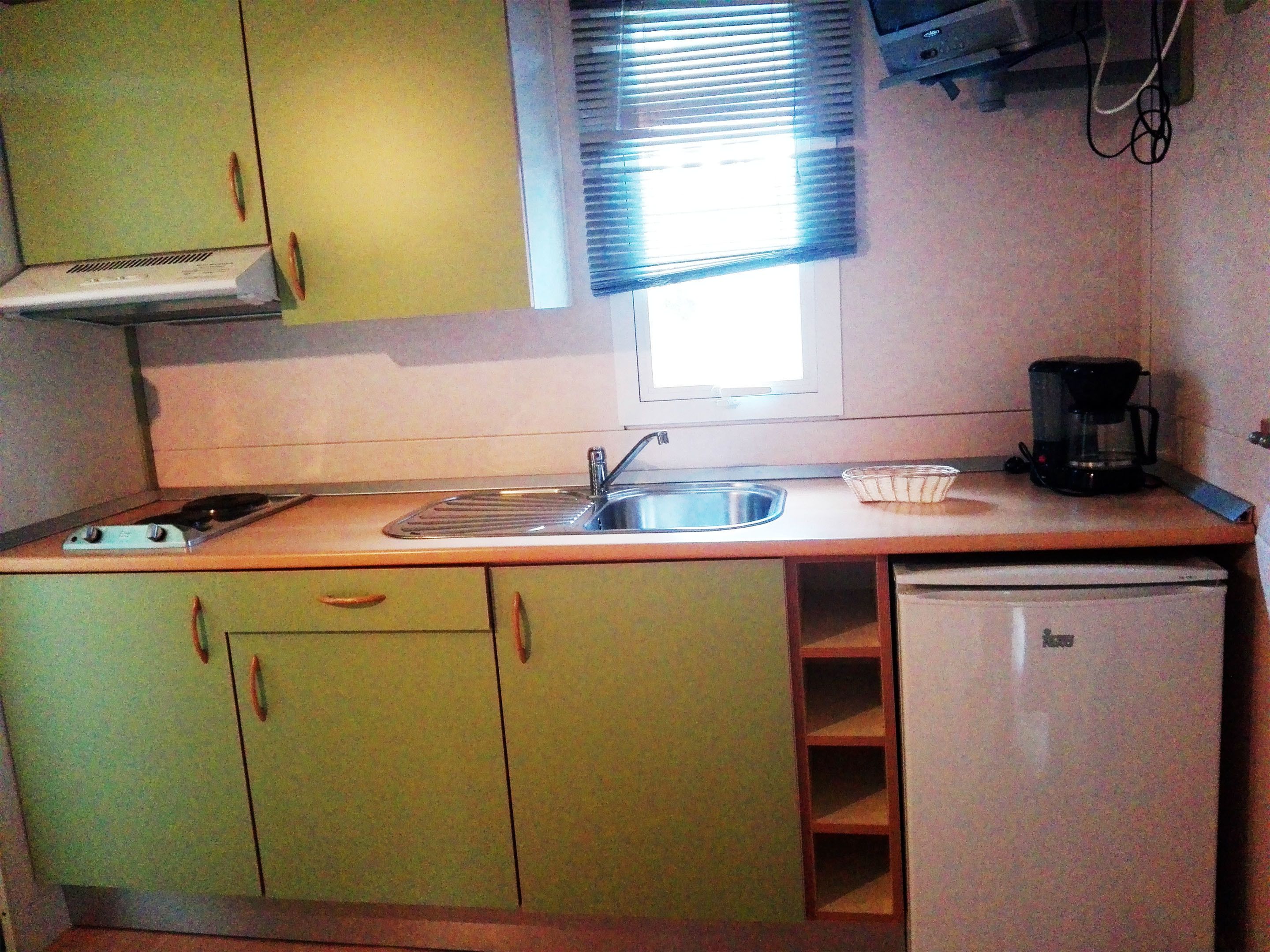 A compact kitchen with a sink, stove, and a small refrigerator.