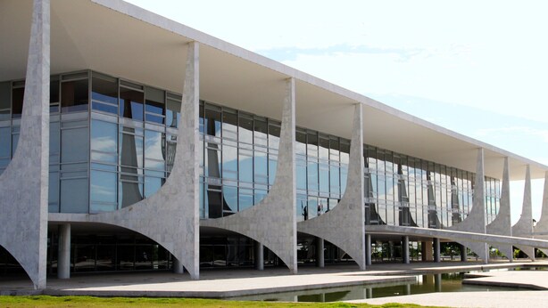 A modern building with a flat roof, large glass windows, and a central water feature.