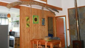 A wooden interior with a dining table, kitchen area, and a large wooden beam structure. - Cabaña Fau Wualmapu (Pucón)