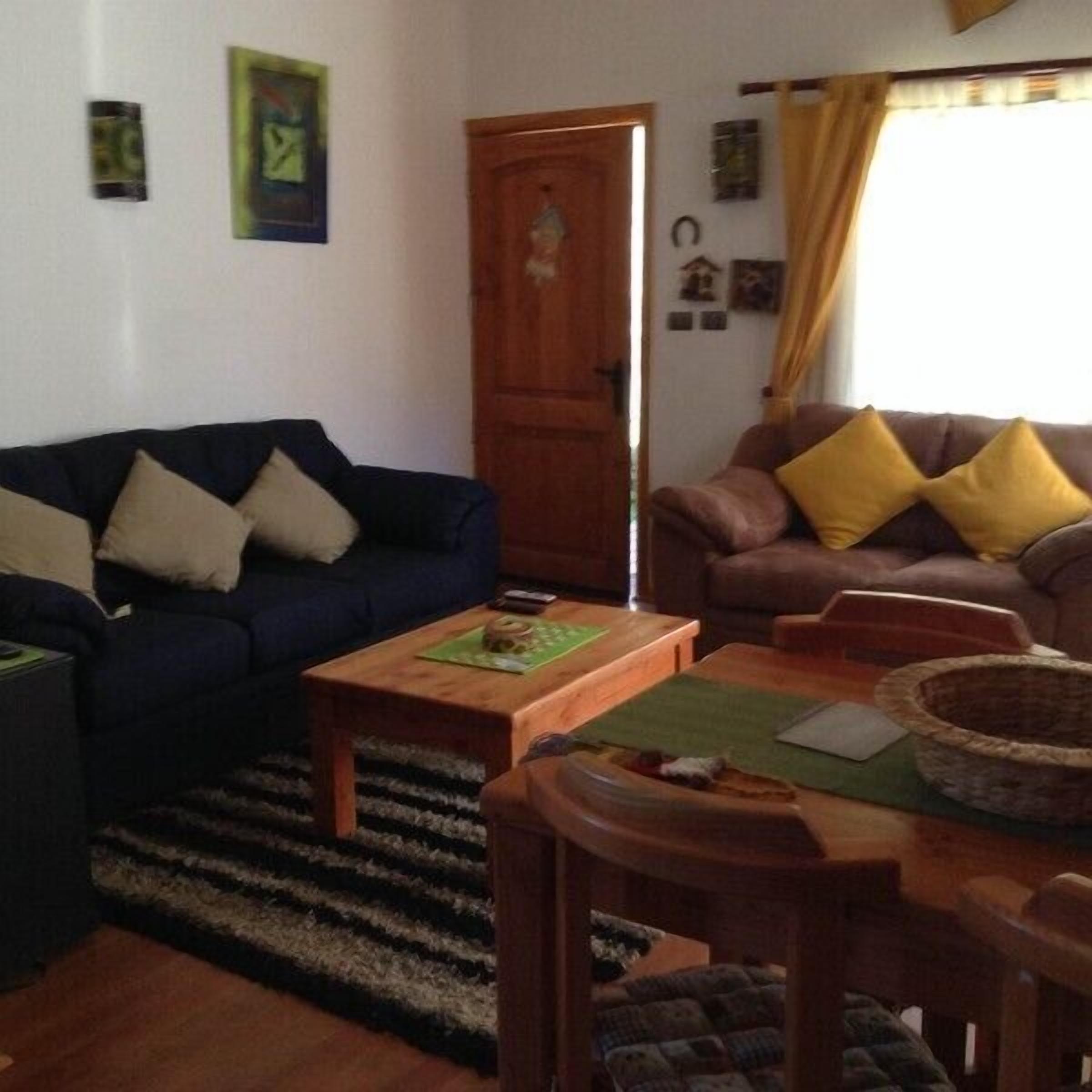A living room with a dark blue sofa, a brown sofa with yellow cushions, a wooden coffee table, and a wicker basket.