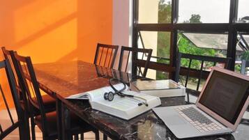 A dining table with chairs, a laptop, a book, and a stethoscope.