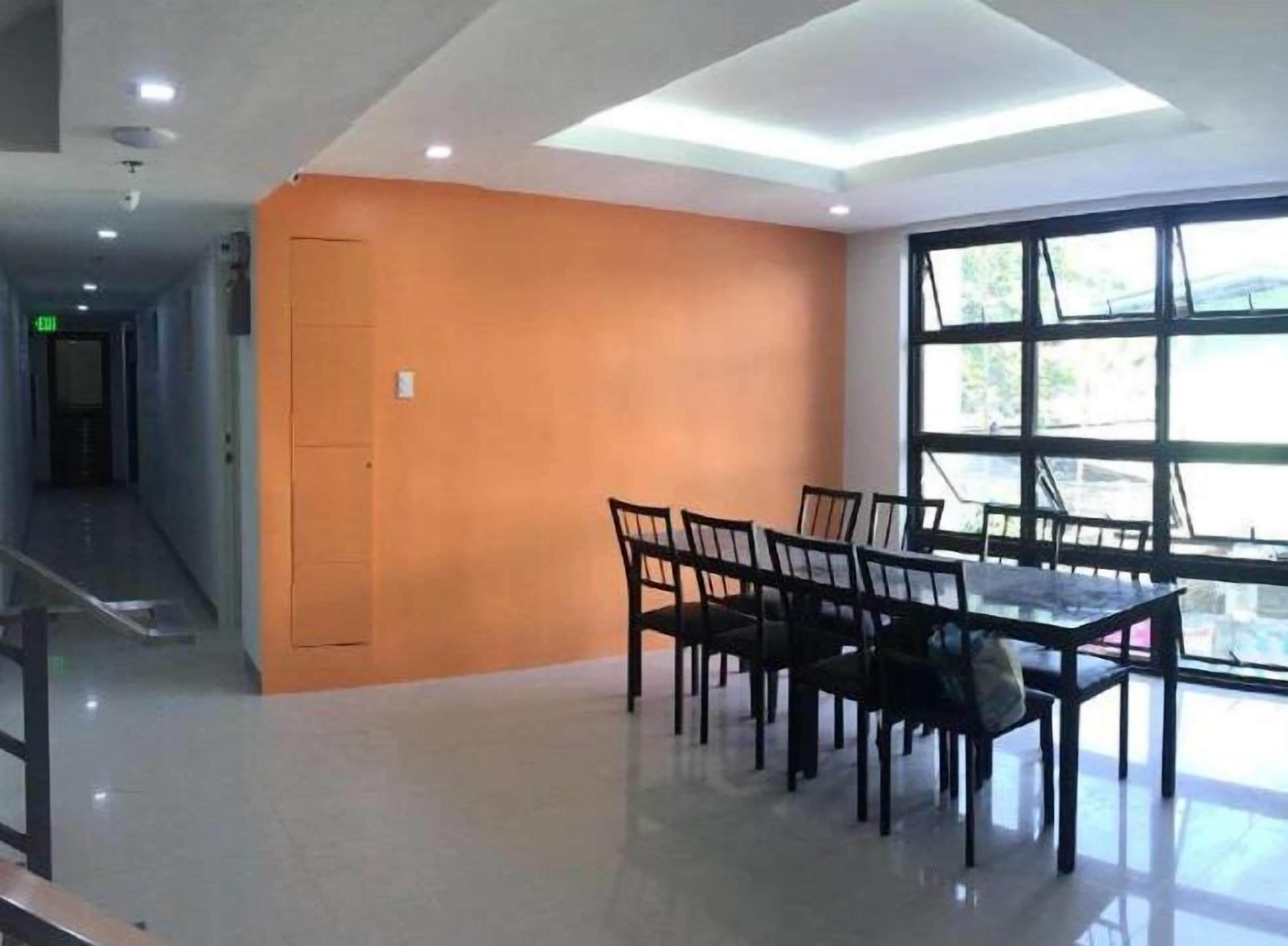 Un interior moderno con un área de comedor que incluye una mesa y sillas, una escalera, y un gran ventanal con vistas.