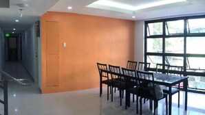 A modern interior with a dining area featuring a table and chairs, a staircase, and a large window with a view. - RF Suites (Cebu City)