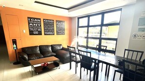 Een moderne woonkamer met een bank, salontafel en een eethoek. Op de muur hangen motiverende posters en een raam zorgt voor natuurlijk licht.