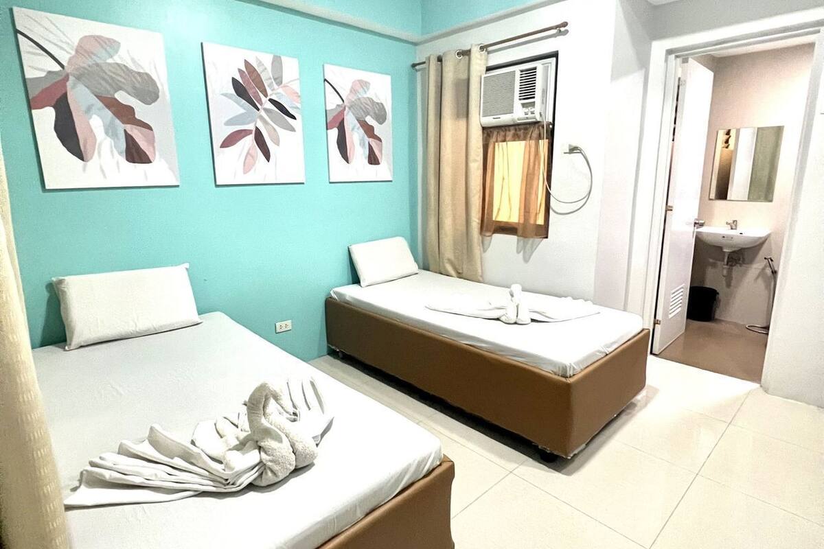 A hotel room with two beds, a bathroom, and artwork on the wall.
