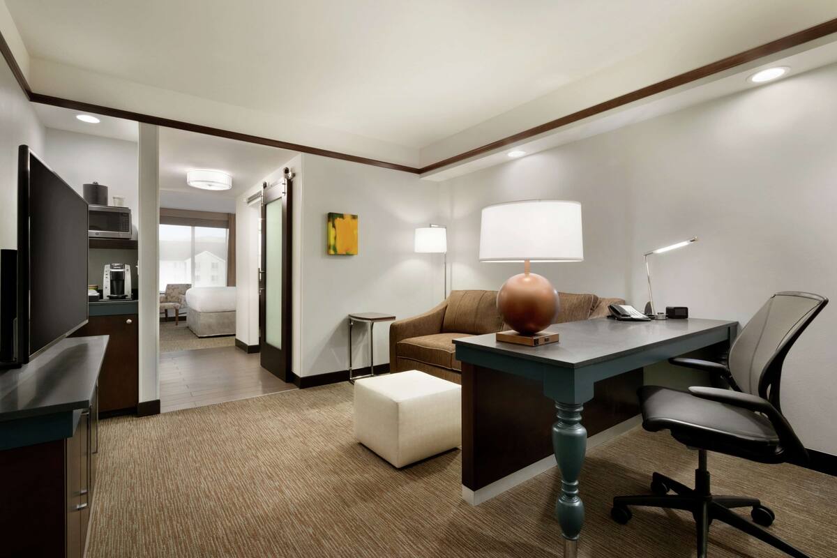Ein Hotelzimmer mit Schreibtisch, Stuhl, Fernseher und einer Sitzecke.
