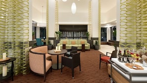 A hotel lobby with a seating area, a bar, and a decorative wall. - Hilton Garden Inn Medford, OR  (Medford)