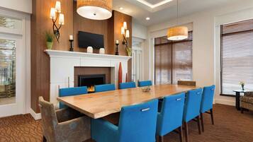 A conference room with a long wooden table, blue chairs, a fireplace, and wall-mounted lighting.
