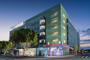 Un hotel moderno con facciata in vetro, numerosi balconi e una segnaletica ben visibile per "Hampton Inn & Suites".