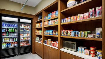 A well-stocked pantry with shelves of snacks, beverages, and a microwave.