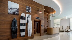 Un espace d’accueil avec des panneaux de bois, des planches de surf et un panneau indiquant l’emplacement d’une boutique de confiseries.