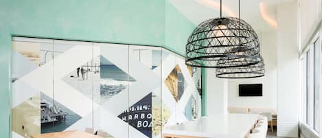 Un interior moderno con un diseño geométrico en la pared, una mesa de madera y una lámpara colgante.