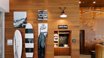 Pared de madera con tablas de surf, un letrero que dice 'TREAT SHOP' y un letrero que dice 'Bienvenido a Santa Mónica'.