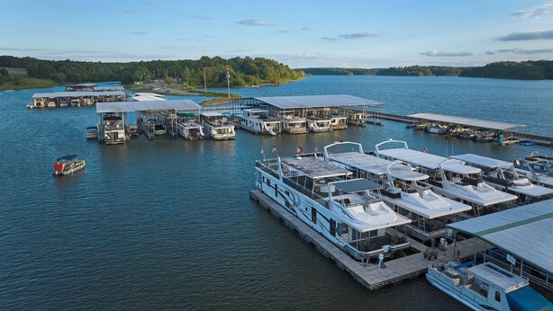 A marina with several boats docked, a large white boat with a covered deck, and a dock with a covered area. - Barren River Lake State Resort Park (Lucas)
