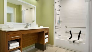 A modern bathroom with a wooden vanity, a large mirror, and a white bathtub with a showerhead.