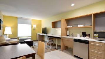 A compact kitchen with a dining area, a dishwasher, and a TV.