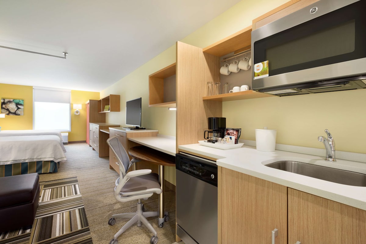 Une chambre d’hôtel équipée d’une kitchenette, d’un lit, d’un bureau et d’une chaise.