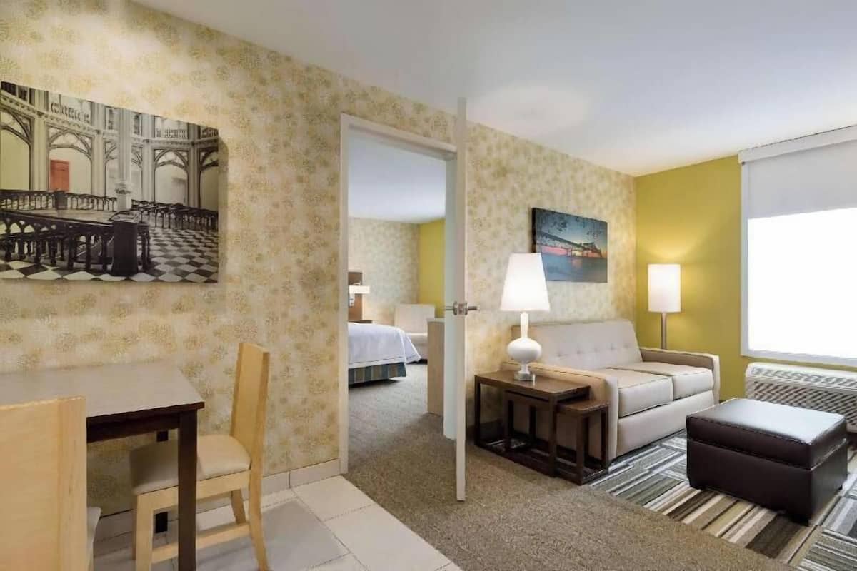 Une chambre d’hôtel avec un sol à carreaux, un lit, un canapé, un bureau et une chaise.