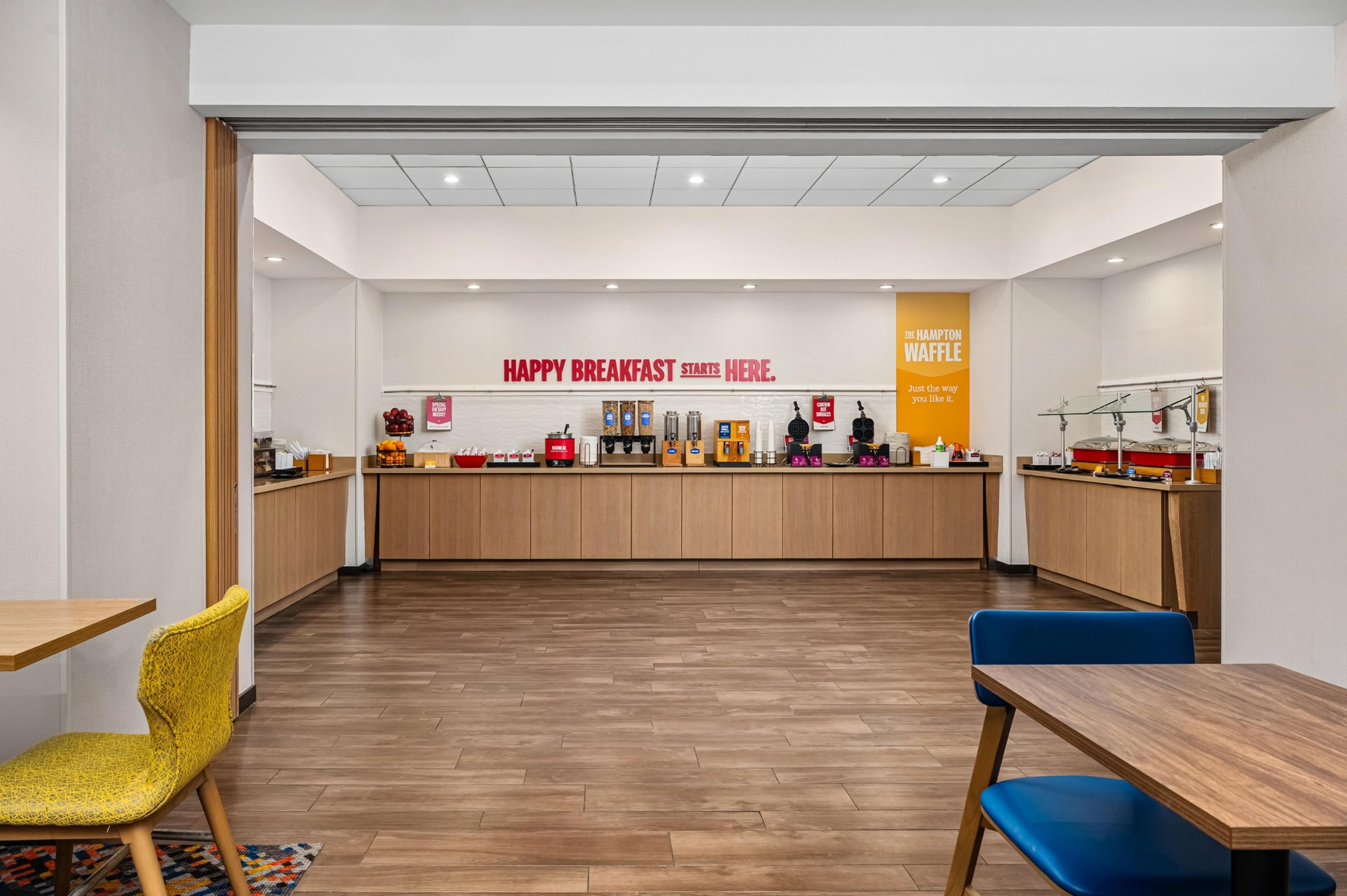 Un área de desayuno con mostrador, asientos y un letrero que dice 'HAPPY BREAKFAST STARTS HERE'.