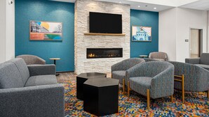 A modern lounge area with a stone fireplace, comfortable seating, and artwork on the walls. - Hampton Inn Chicago North-Loyola Station (Chicago)