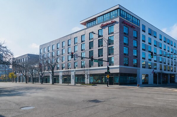 A modern hotel with a prominent 'Hampton Inn' sign, large windows, and a corner location at an intersection. - Hampton Inn Chicago North-Loyola Station (Chicago)