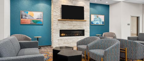 A modern lounge area with a stone fireplace, comfortable seating, and artwork on the walls.