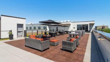 A rooftop terrace with outdoor seating, a pool, and a view of the city skyline.