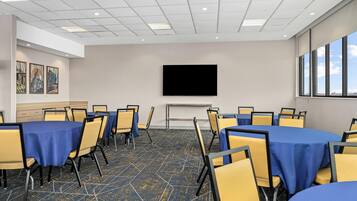 A conference room with tables and chairs, a flat-screen TV, and artwork on the wall.