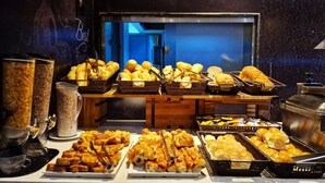 Un buffet proposant une variété de plats, notamment du pain, des pâtisseries, ainsi qu’un coin café.