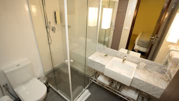 A modern bathroom with a glass-enclosed shower, a white toilet, and a marble countertop sink.