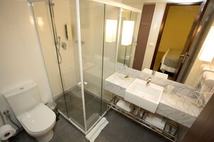 Een moderne badkamer met een douchecabine van glas, een wit toilet en een wastafel met een marmeren blad.