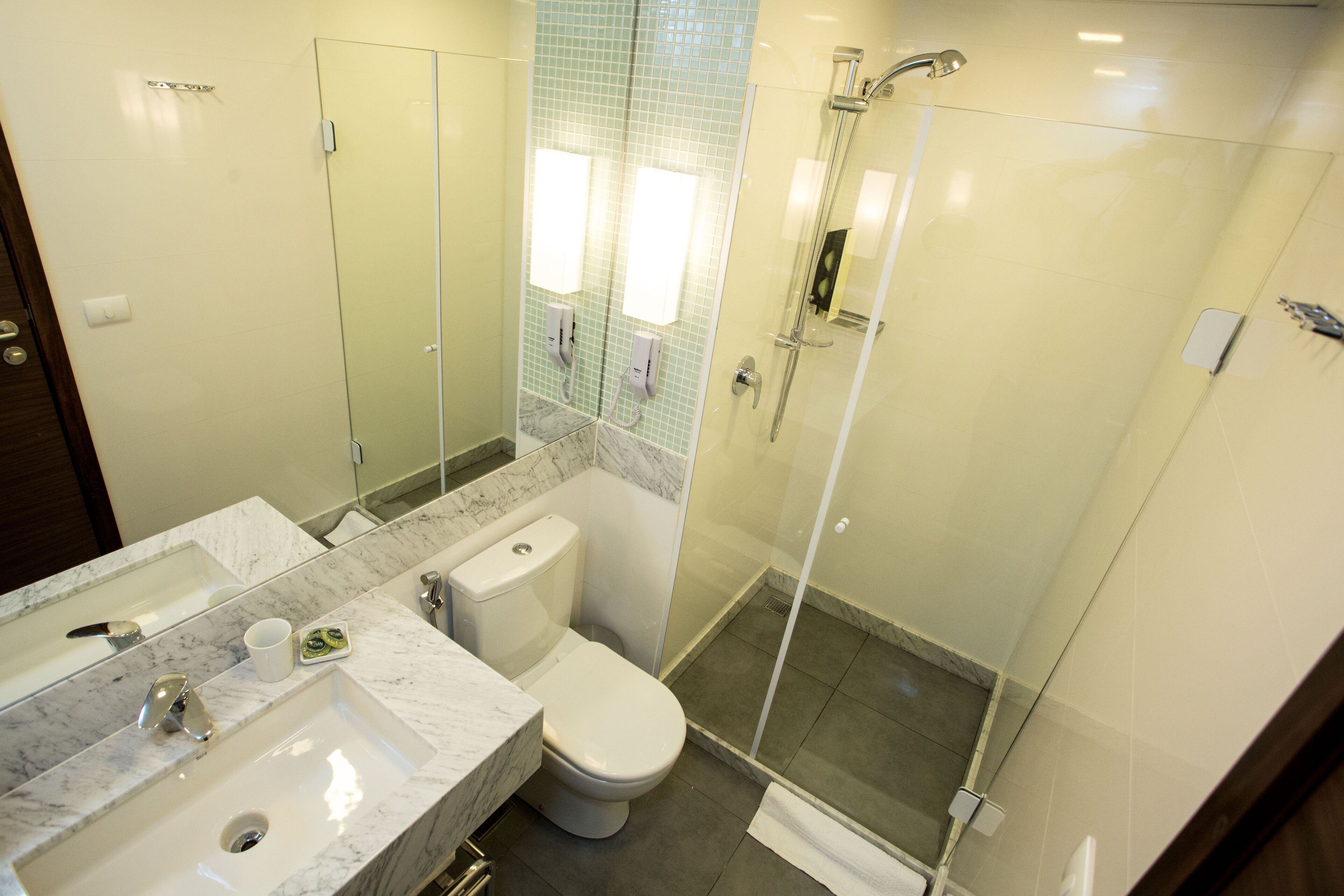 A modern bathroom with a marble sink, a toilet, and a glass-enclosed shower.