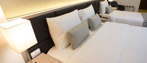 A hotel room with two beds, a nightstand with a lamp, and a bedside table with a phone.