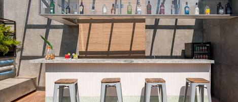 Una zona de bar con taburetes, una barra y una variedad de botellas.