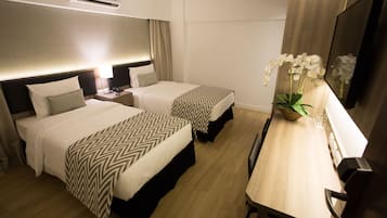 Een hotelkamer met twee bedden, een bureau, een stoel, een televisie en een potorkidee.