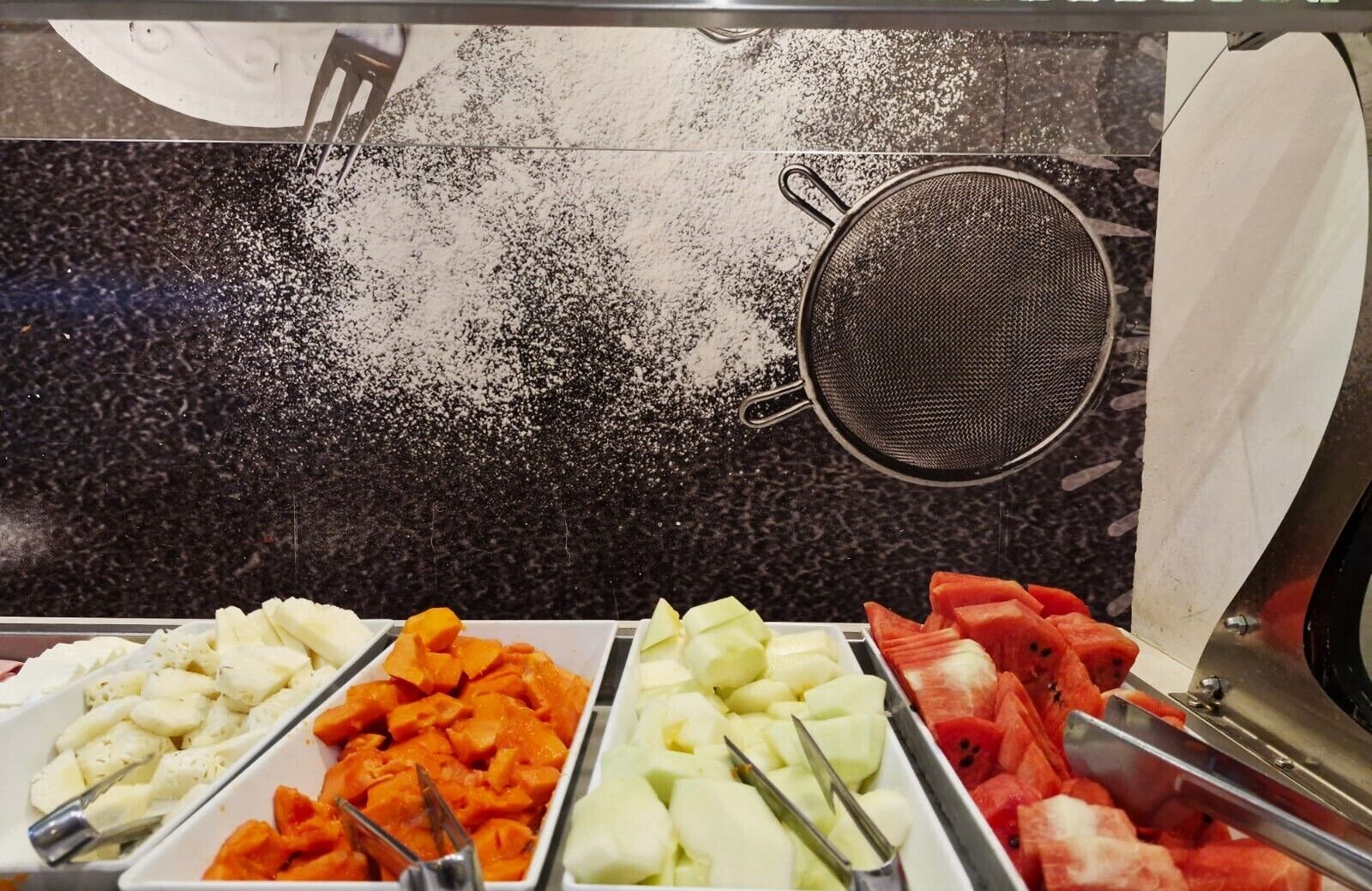 Un buffet proposant une variété de fruits et de légumes, notamment des pommes, des carottes, du céleri et des pastèques.