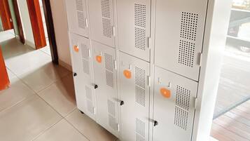 A row of white lockers with numbered compartments, a ceiling fan, and a tiled floor.