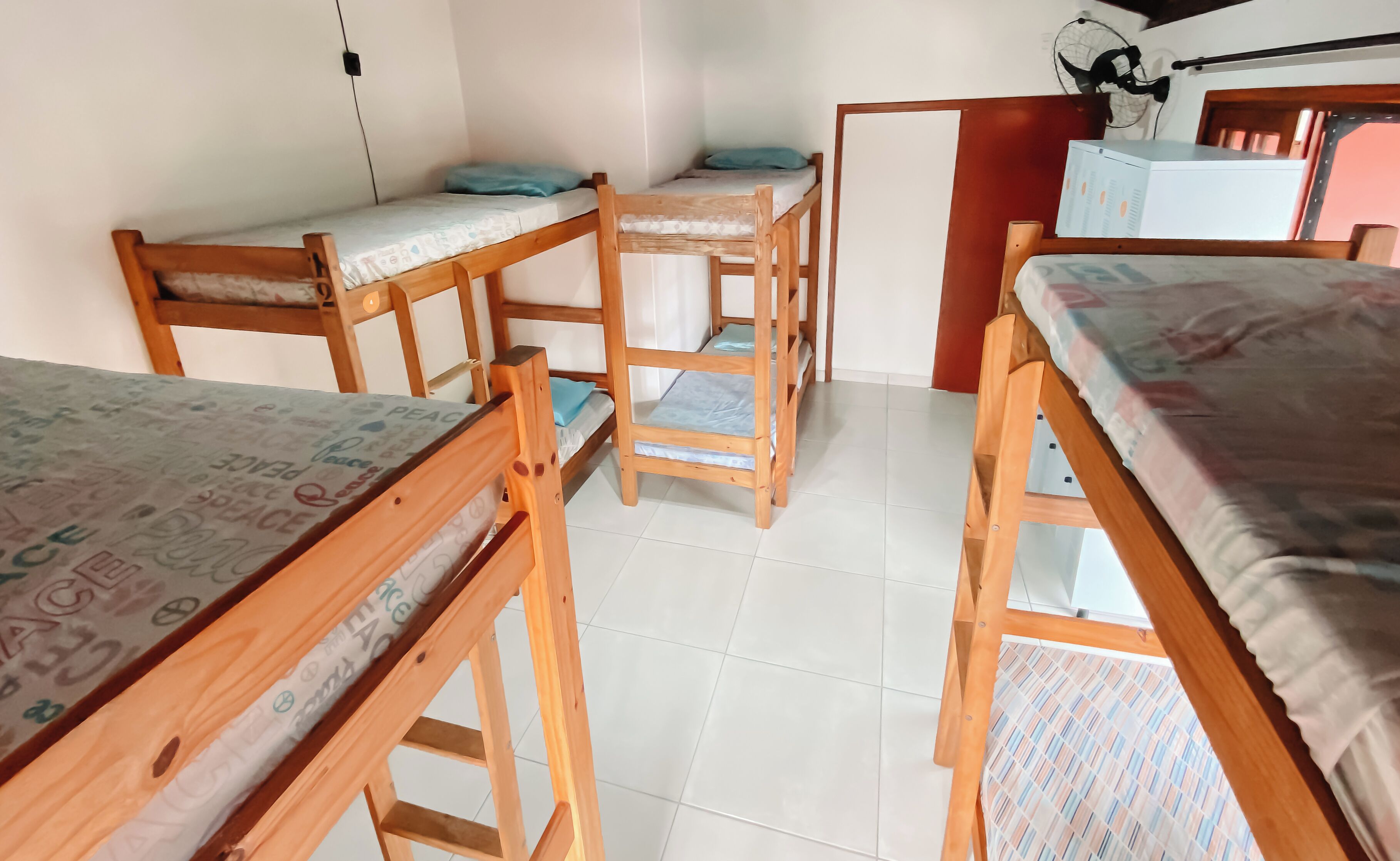 A dormitory room with bunk beds, a desk, and a chair.