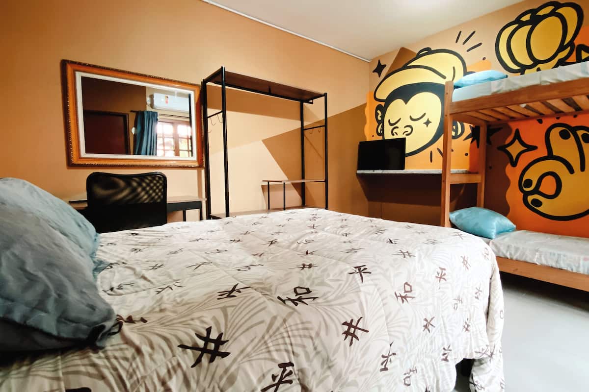 A dormitory room with bunk beds, a desk, a chair, and a mirror.