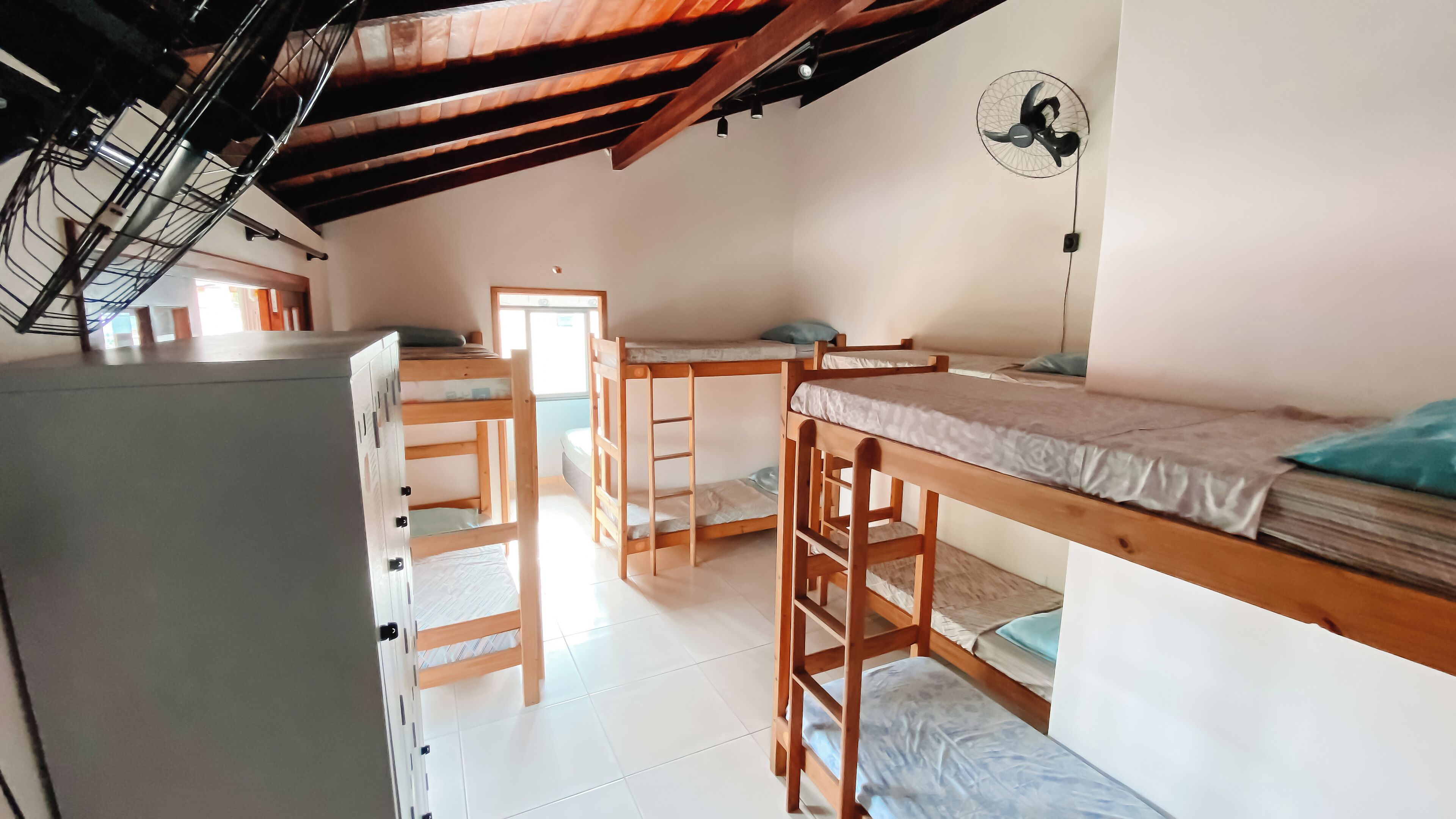 Un dormitorio con literas, un escritorio, una silla y un ventilador.