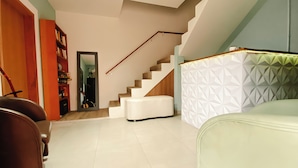 A modern living room with a staircase, a sofa, and a bookshelf. - Sagui Hostel (Florianópolis)