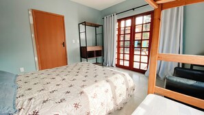 A bedroom with a bed, a wardrobe, a wooden bench, and a window with curtains. - Sagui Hostel (Florianópolis)