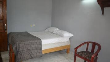Un dormitorio con cama, una silla y un aplique de pared.