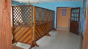 A room with a wooden partition, a ceiling fan, and a door with a sign. - Victoria Guest House (Limbe)