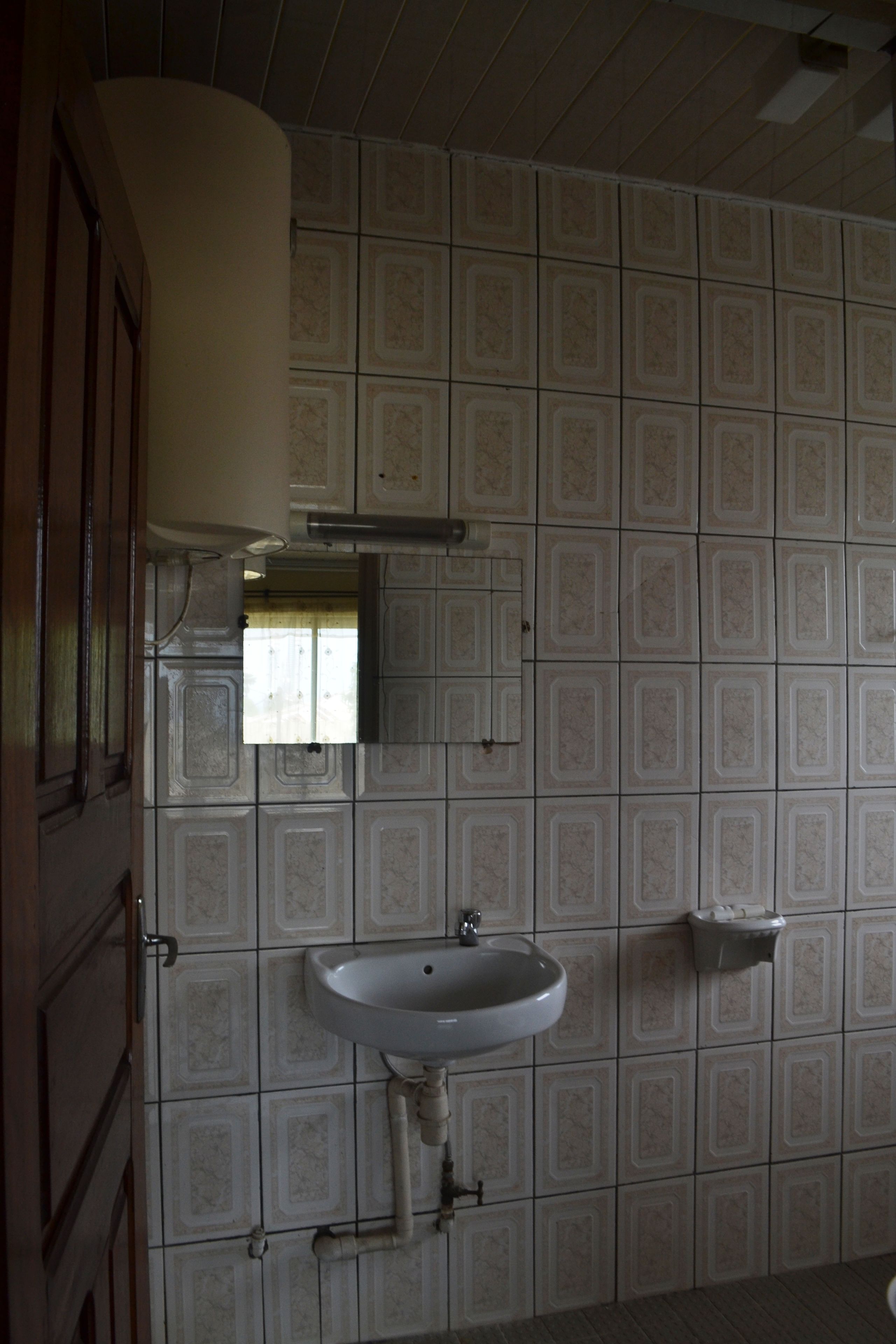 Un baño con lavamanos, espejo y paredes de azulejos.