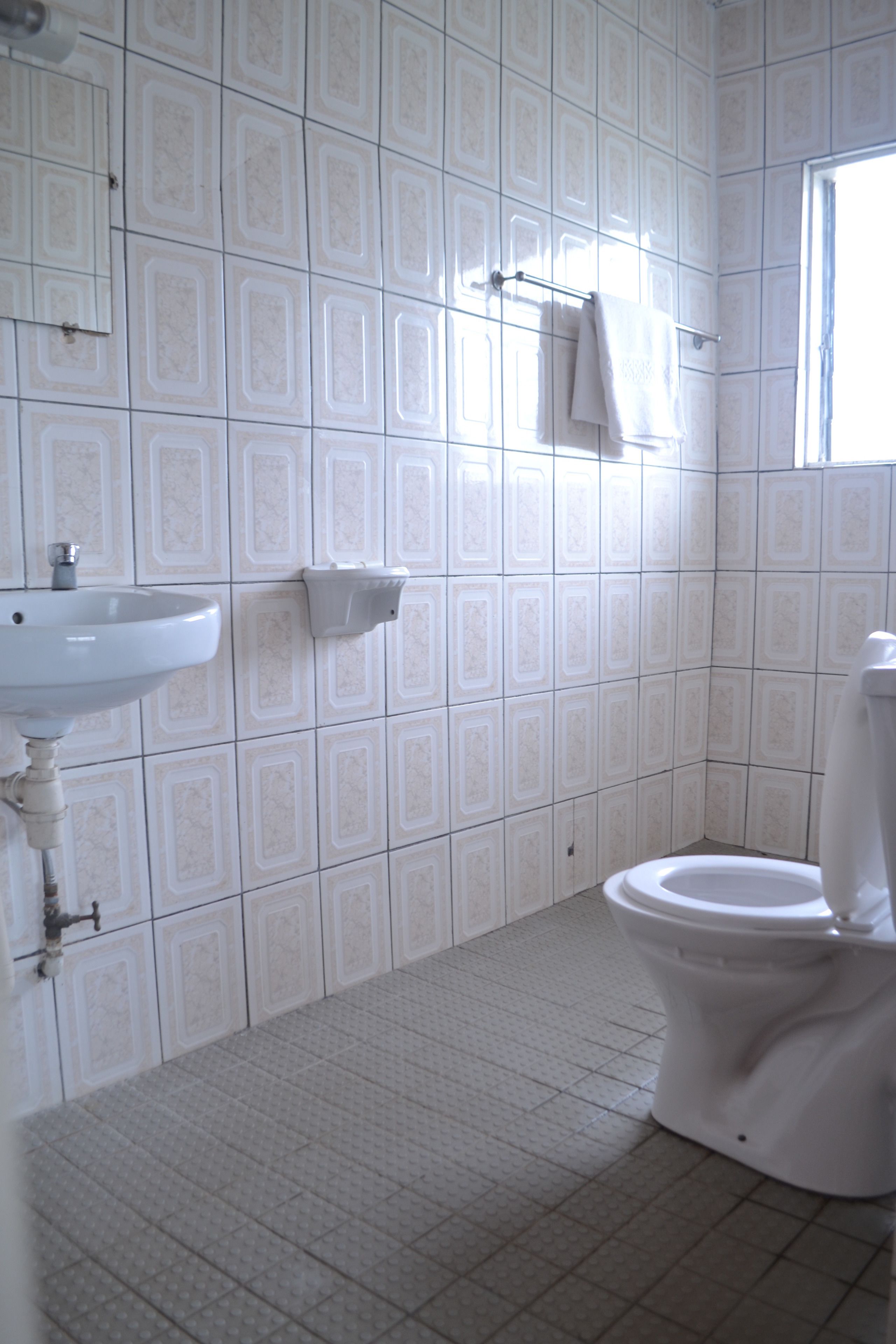 A bathroom with a sink, toilet, and a window.