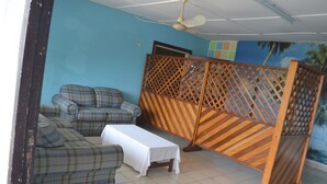 A room with a blue wall, a ceiling fan, a white table, and a sofa set. - Victoria Guest House (Limbe)